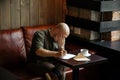 Young serious fashionable man sitting alone and writing a letter Royalty Free Stock Photo