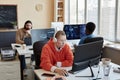 Young serious female IT manager in headphones clicking on mouse