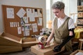 Young serious female worker of warehouse sealing packed box with cellotape Royalty Free Stock Photo