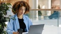 Young serious focused millennial african american girl business woman freelancer manager specialist sitting at table in Royalty Free Stock Photo