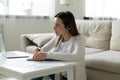 Focused woman in headphones watch webinar on laptop writing notes