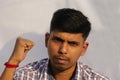 Young serious looking Indian man close up face portrait with fist up view on isolated dark background.