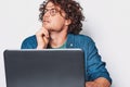 Young serious man with curly hair sitting at table working at laptop. Businessman wearing round glasses and working on laptop Royalty Free Stock Photo