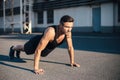 Young serious man doing pushups outdoor on industrial background