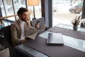 Young serious man in fashion beige jacket and roll neck sitting at the table Royalty Free Stock Photo