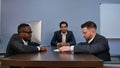 Young serious man holding papers, reading them attentively, during meeting in office