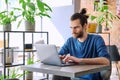 Young serious man working, studying, typing on laptop sitting in coworking cafe Royalty Free Stock Photo