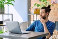 Young serious man working, studying using laptop sitting in coworking cafe Royalty Free Stock Photo