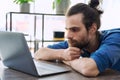 Young serious man working, studying using laptop sitting in coworking cafe Royalty Free Stock Photo