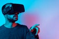 Young serious man working with virtual reality glasses raising hands and touching something, using new and innovative technology Royalty Free Stock Photo