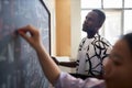Young serious man in casualwear looking at formulas on blackboard Royalty Free Stock Photo