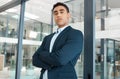 Young serious mixed race businessman standing with his arms crossed alone at work. One confident hispanic male boss Royalty Free Stock Photo