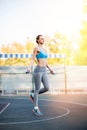 Young serious sportswoman exercising with skipping rope on stadium