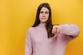 Young serious strict disappointed millennial woman show thumb down dislike gesture refusing say no, wearing pink knitted sweater