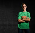 Young serious teen boy in green t-shirt, jeans and glasses standing and looking camera over dark background Royalty Free Stock Photo