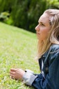 Young serious woman looking ahead while lying on the grass Royalty Free Stock Photo