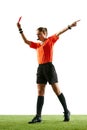 Young serious woman, soccer referee blowing a whistle and showing red card as dismissal symbol against white studio Royalty Free Stock Photo