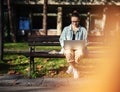A young serious woman student sitting on a bench in the park and typing on her laptop on a sunny day in university campus Royalty Free Stock Photo
