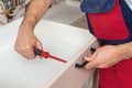 Young service contractor assembling new furniture in kitchen