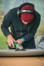 Young service man is using an angle grinder with a wire brush to clean the underside of an old vintage car about to be restored