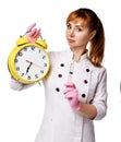 Young severe doctor in medical gown holds syringe and alarm clock reminding of the importance of following a schedule