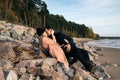 Young sexual couple in love lying down on stones at the beach, hugging kissing and enjoy each other. Royalty Free Stock Photo