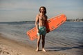 Young beach lifeguard standing on the sand with life-saving