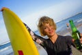 Young beautiful and happy surfer woman holding yellow surf board smiling cheerful drinking beer bottle enjoying summer holida Royalty Free Stock Photo