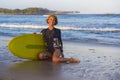 Young beautiful and happy surfer woman sitting on beach sand holding yellow surf board smiling cheerful enjoying summer holid Royalty Free Stock Photo