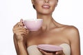 Young beautiful woman with dark hair picked up holding a ceramic cup and saucer pale pink drink tea or coffee on a white back Royalty Free Stock Photo