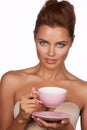 Young beautiful woman with dark hair picked up holding a ceramic cup and saucer pale pink drink tea or coffee on a white back Royalty Free Stock Photo