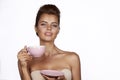 Young beautiful woman with dark hair picked up holding a ceramic cup and saucer pale pink drink tea or coffee on a white back Royalty Free Stock Photo