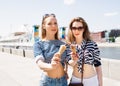 Young blonde best friends girls eating ice cream in summer hot weather in sunglasses have fun and good mood looking in camera Royalty Free Stock Photo