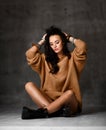 Young blonde fashion woman sitting on floor in brown knitted blouse Royalty Free Stock Photo