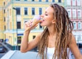 Young blonde girl with dreads eating multicolored ice cream in waffle cones in summer evening, joyful and cheerful. Europea Royalty Free Stock Photo