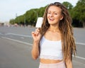 Young blonde girl with dreads eating white ice cream in summer hot evening, joyful and cheerful.