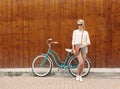 Young blonde girl with long hair in green sunglasses standing near vintage green bicycle have fun and good mood looking in ca Royalty Free Stock Photo