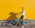 Young blonde girl is standing near the vintage green bicycle with brown vintage bag