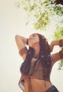 Young boho style woman enjoy sunny day relaxing in summer park, hands up and smiling