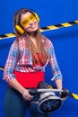 Young builder girl in chechered shirt, yellow earmuffs and Royalty Free Stock Photo