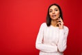 Young sexy charming beautiful brunette woman with sincere emotions wearing casual sweater isolated over red background