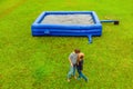 Young couple on the background of a large inflatable blue trampoline on green grass Royalty Free Stock Photo