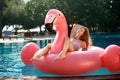 Young and girl having fun and laughing on an inflatable giant pink flamingo pool float mattress in a bikini Royalty Free Stock Photo