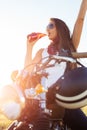 Young girl sitting on vintage custom motorcycle and drinking juice . Outdoor lifestyle portrait Royalty Free Stock Photo