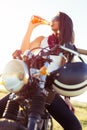 Young girl sitting on vintage custom motorcycle and drinking juice . Outdoor lifestyle portrait Royalty Free Stock Photo