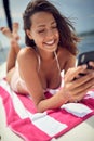 A young sexy girl is using a smartphone while is taking a sunbath. Summer, sea, vacation Royalty Free Stock Photo