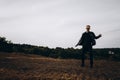 Young sexy man in leather jacket and sunglasses standing outdoor. Dark silhouette against grey sky