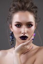 Young sexy model with professional makeup, perfect skin, high volume hairstyle. Violet eye arrows, dark violet lips