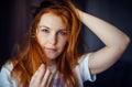 Young sexy red-haired girl touches her tousled hair and looks at camera, close-up. Beautiful well-groomed skin and hair. Image for Royalty Free Stock Photo