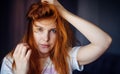 Young sexy red-haired girl touches her tousled hair and looks at camera, close-up. Beautiful well-groomed skin and hair. Image for Royalty Free Stock Photo